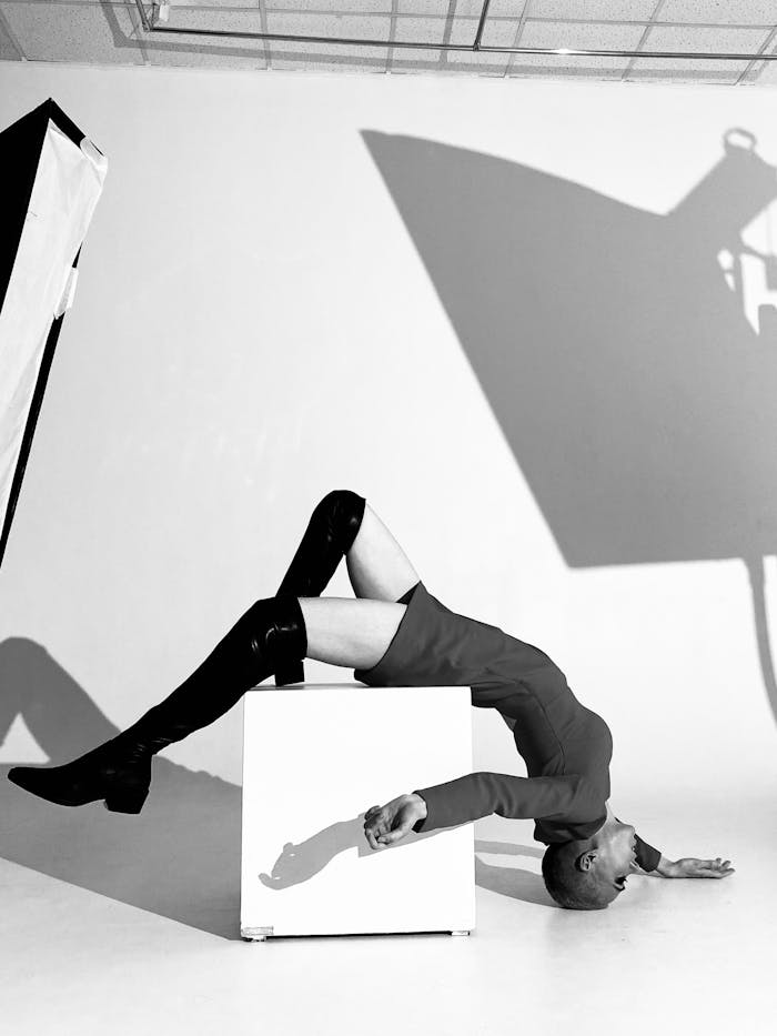 Dramatic black and white fashion shot of a model in a dynamic pose indoors.